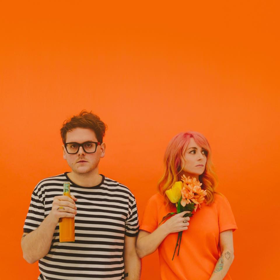 Repeat Repeat duo in front of orange backdrop.