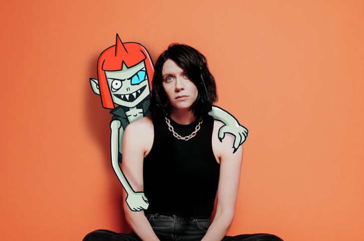K. Flay's Inside Voices EP album artwork. artist sitting in front of orange backdrop with cartoon figure leaning over her.