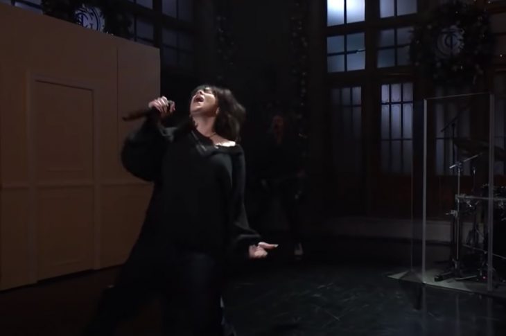 Billie Eilish in black sining on stage at Saturday Night Live