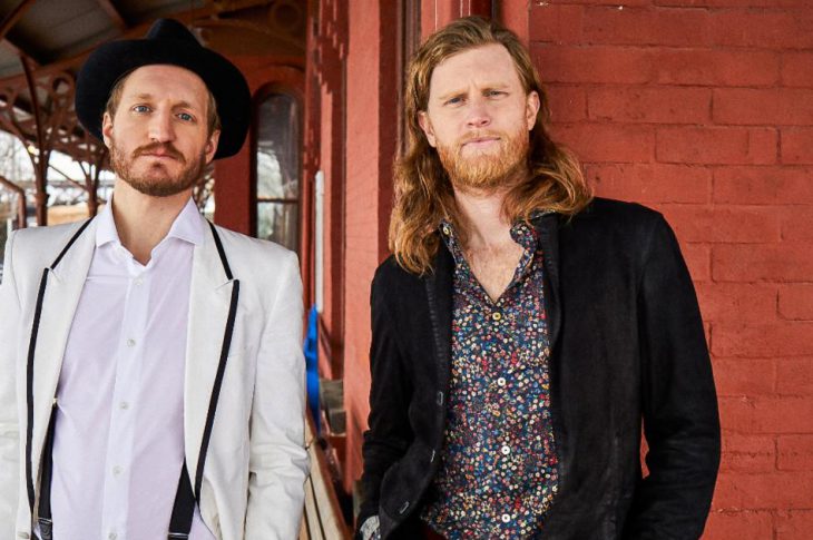 Photo of Jeremiah Fraites and Wesley Schultz of The Lumineers in front of brick wall