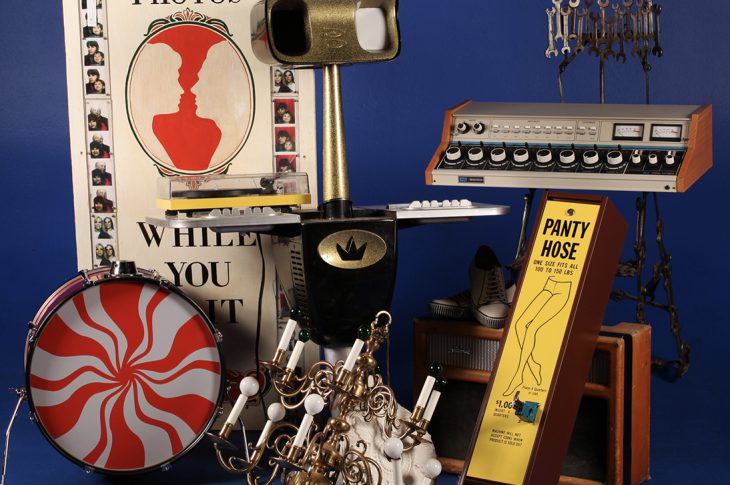 Photo of items from Jack White auction (drums, chandelier, amplifier, etc ) against blue background
