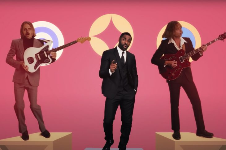 Lime Cordiale and Idris Elba wearing suits performing in front of pink background