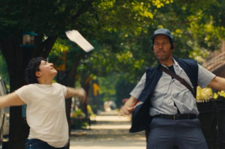 Claud dancing in the street with Paul Rudd, dressed as a letter carrier.