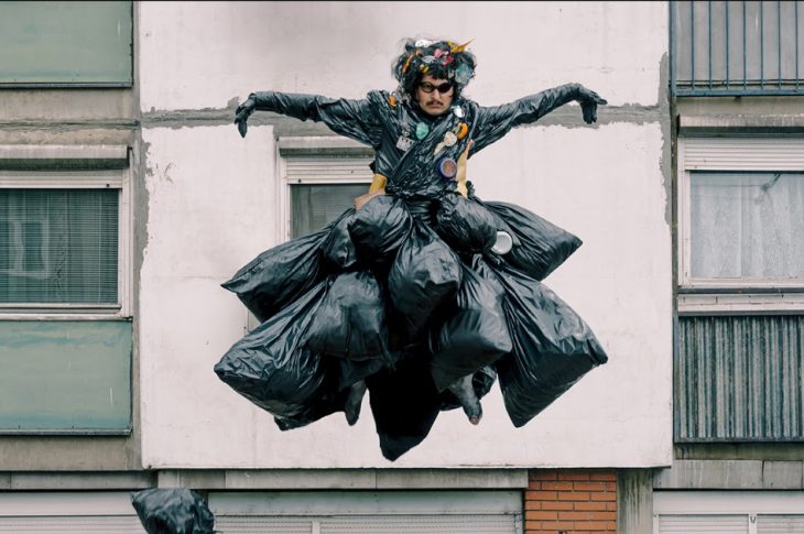 Oliver Tree leaping in the air wearing a gown out of trash bags.