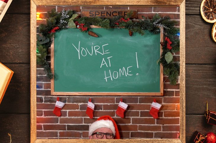 Composite photo of "you're at home" artwork in front of holiday backdrop.