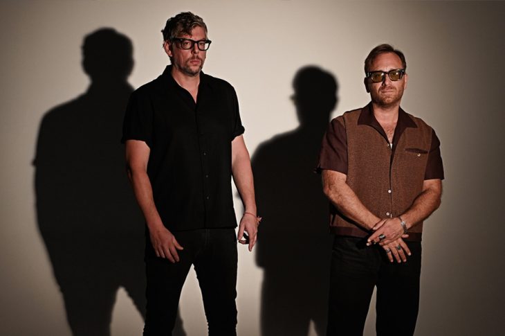 The black keys' Patrick Carney and Dan Auerbach standing against white background.