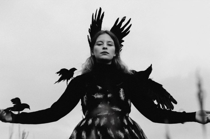 black and white photo of Paris Paloma with arms outstretched with birds landing on their arms