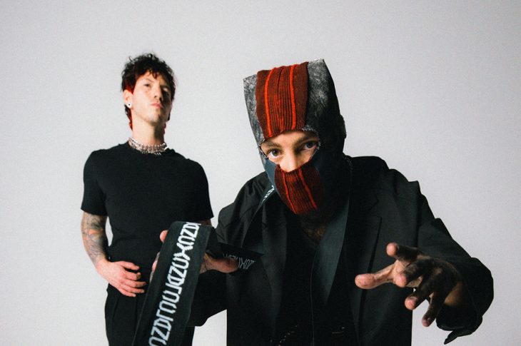 Twenty One Pilots members photographed against white background. One member wearing a ski mask.