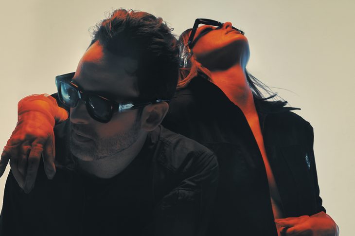 Two people in sunglasses photographed against white background