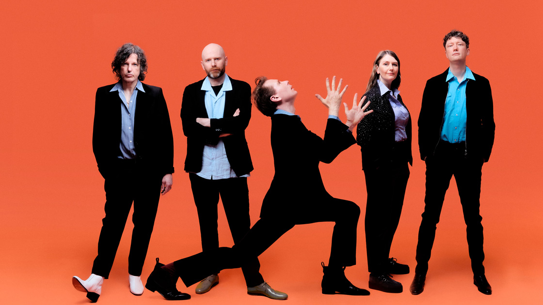 5 people dressed in black photographed against orange background