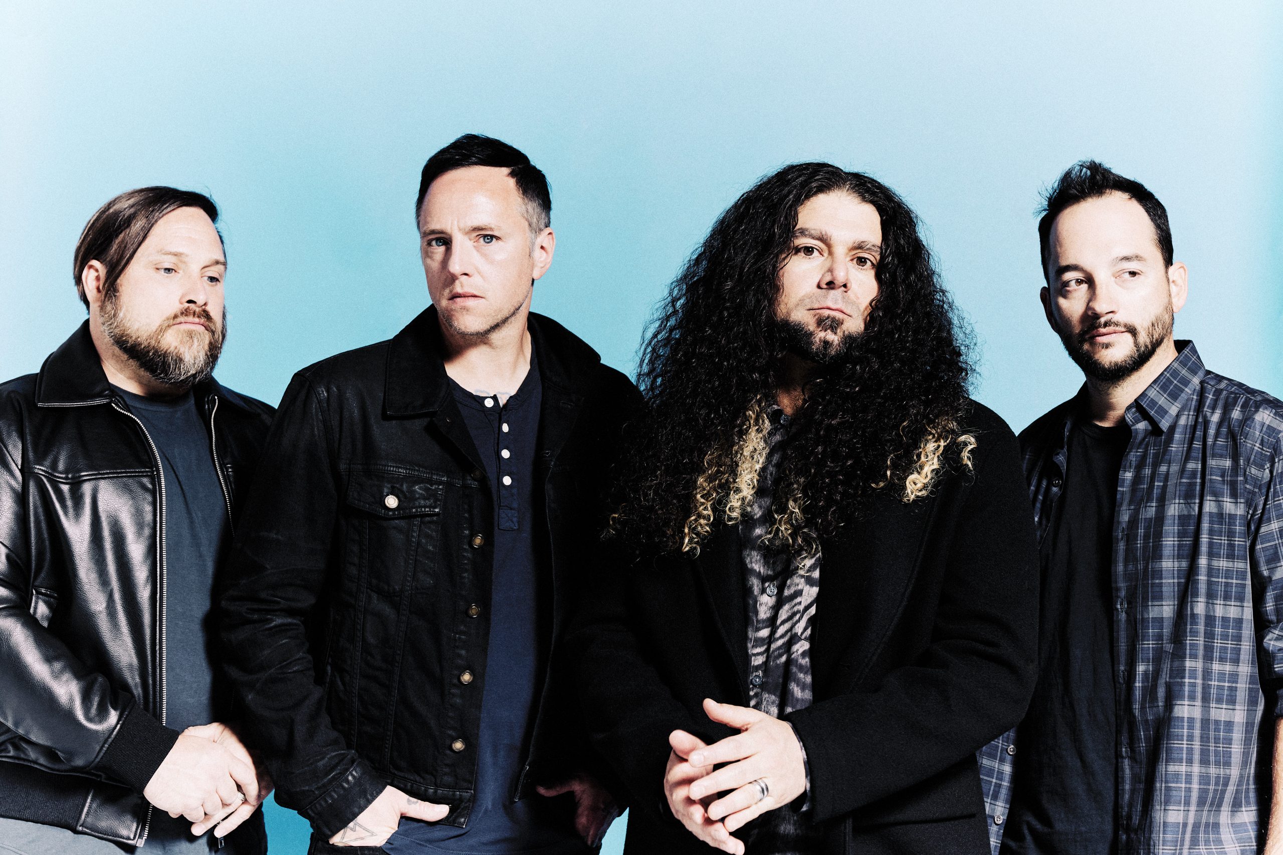 Band members of Coheed and Cambria photographed against blue background.