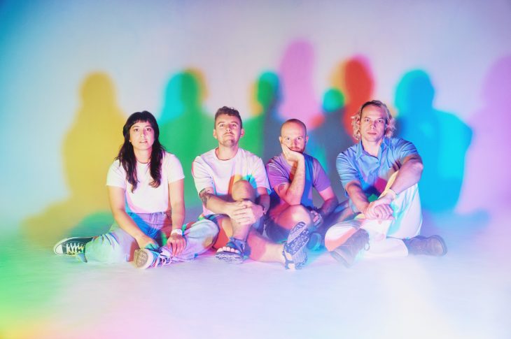 colorful photo of four people sitting on the floor.
