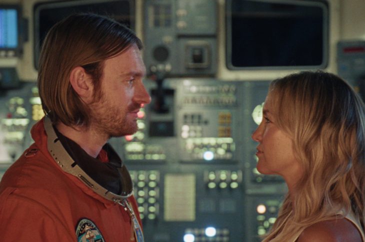 man in spacesuit and woman staring at each other
