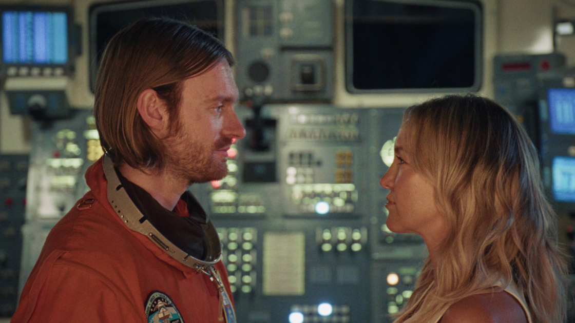 man in spacesuit and woman staring at each other
