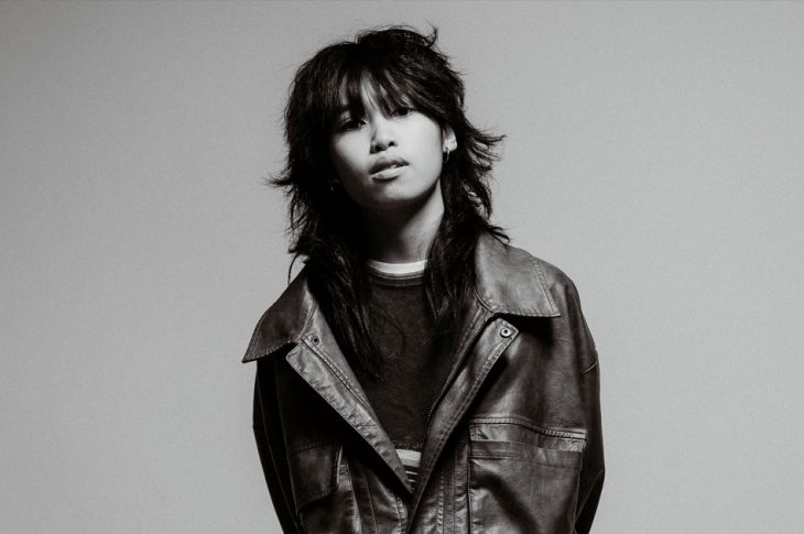 Black and white photo of artist in leather jacket against white backdrop