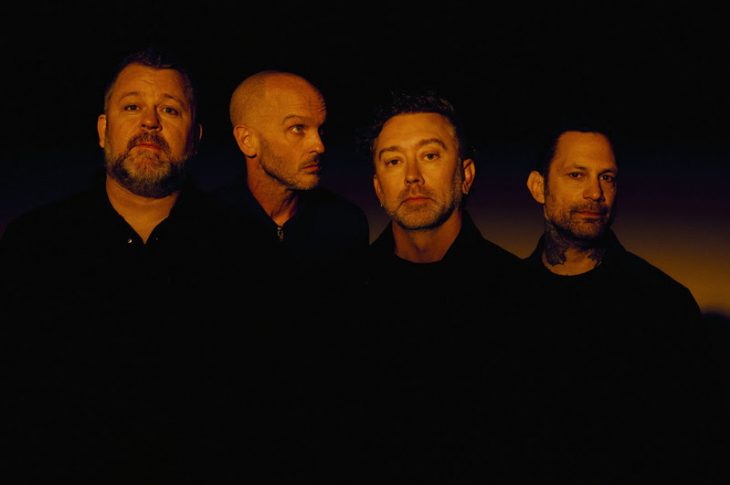four men photographed in orange light