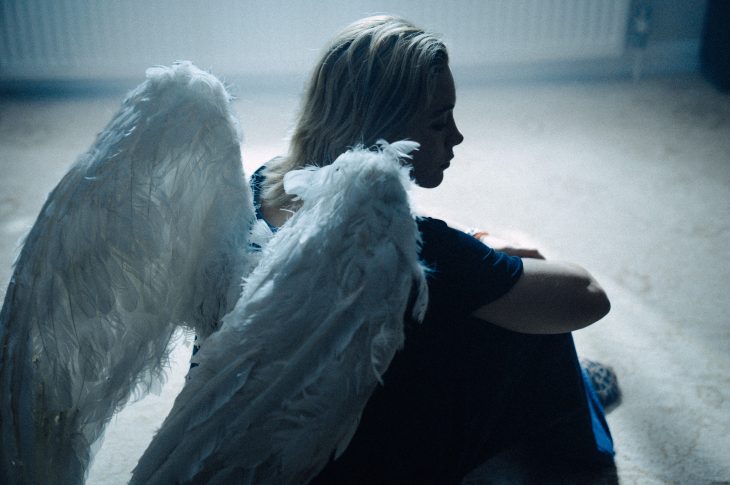 woman dressed as angel sitting on the floor
