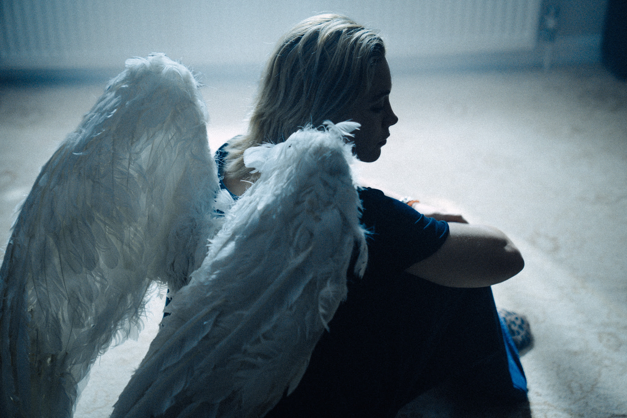 woman dressed as angel sitting on the floor