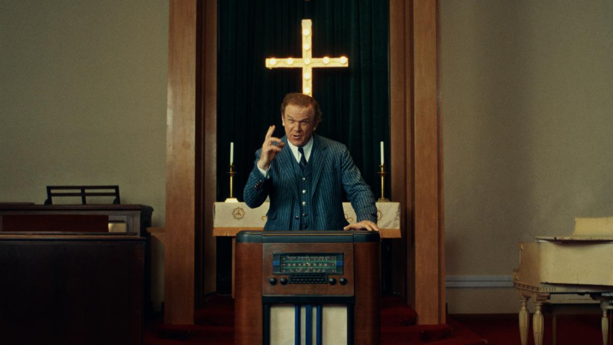 photo of preacher standing behind antique radio