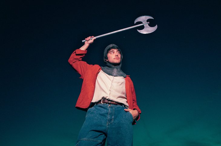 Photo of man stading with battle ax over his head.