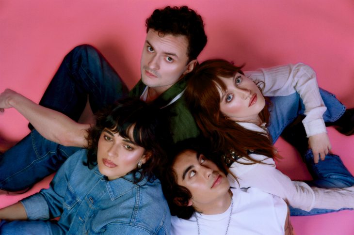 4 people sitting on the floor in a pink room.