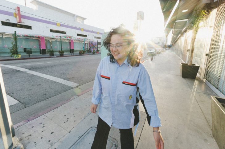 Photo of person walking down the street in sunshine.