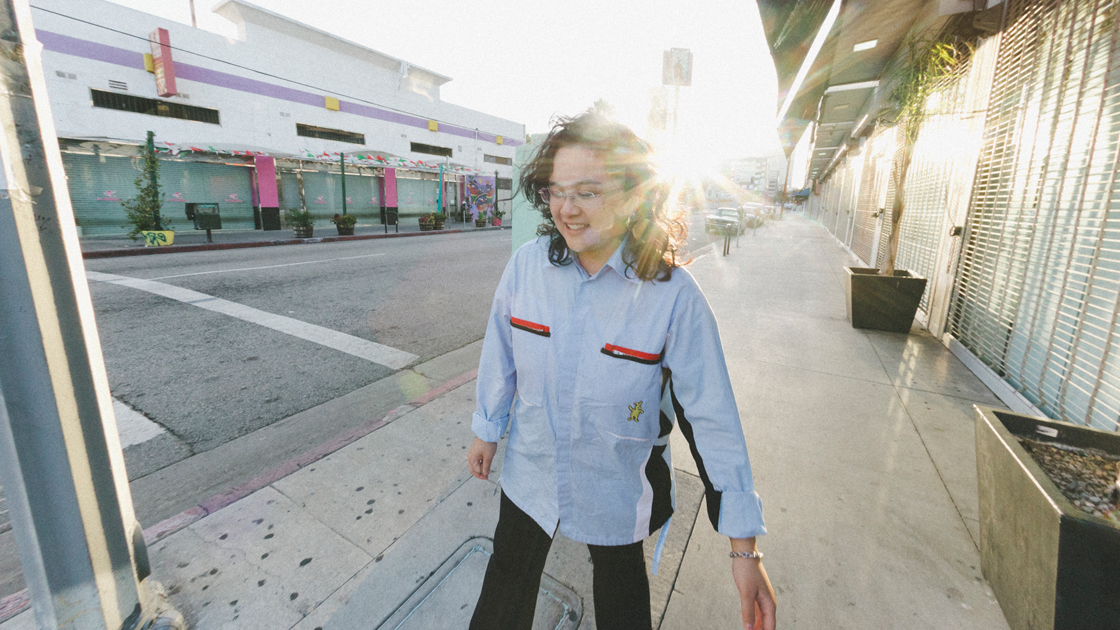 Photo of person walking down the street in sunshine.