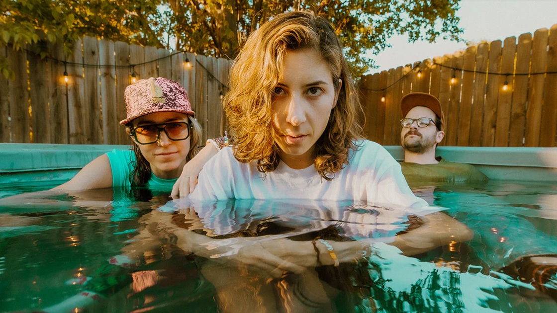 three people sitting fully clothed in a pool.