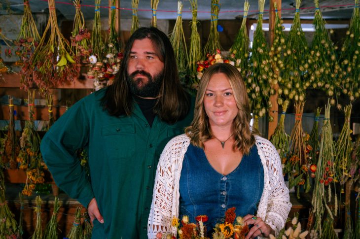 Photo of man and woman standing among flowers