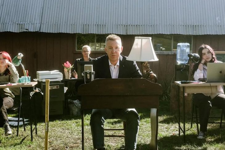 four people sitting at work desks outside