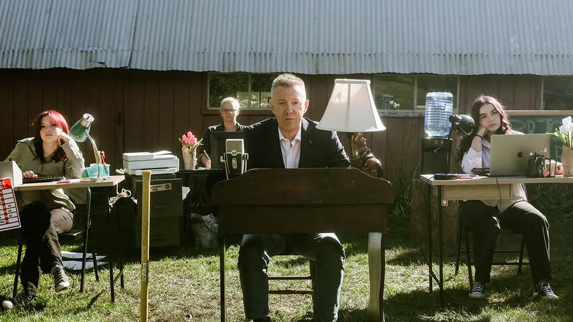 four people sitting at work desks outside