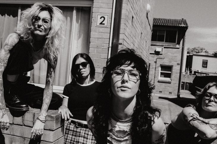black and white photo of 4 women standing around a brick wall