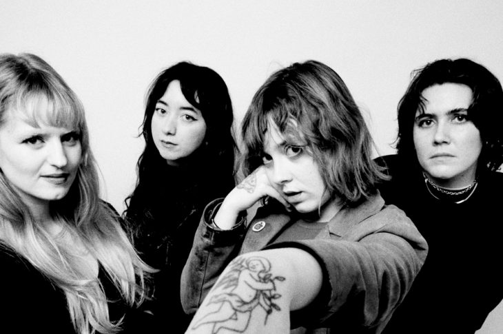 black and white photo of four people photographed against white backgroud