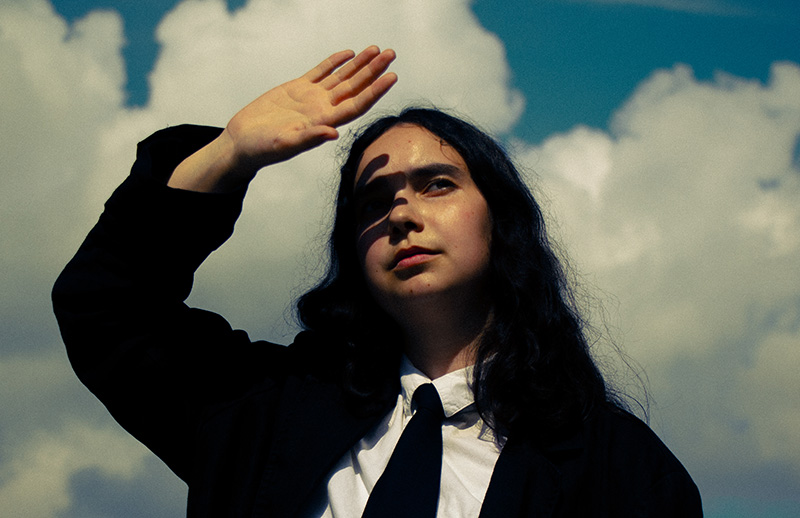Woman photographed against clouds looking into the sun.