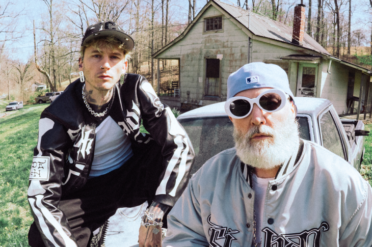 Two men sitting on hood of car