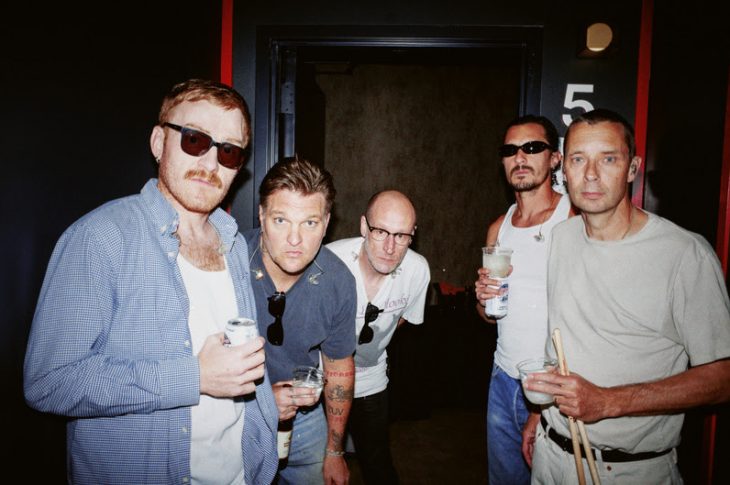 5 men photographed in hallway.