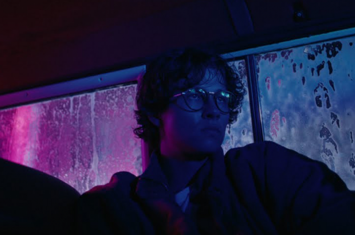 man sitting in car at night bathed in purple light.