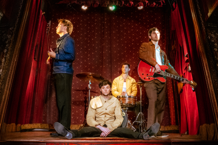 four musicians on stage in a theatre.