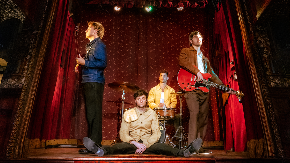 four musicians on stage in a theatre.