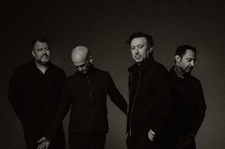 Black and white photo of 4 men in studio