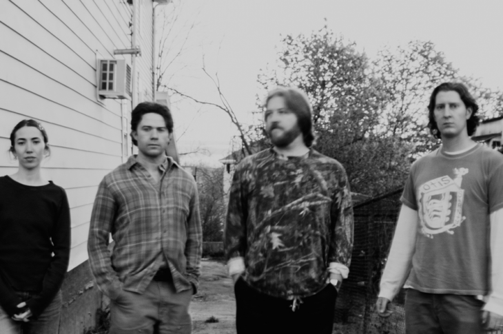 black and white photo of four musicians in an alleyway.