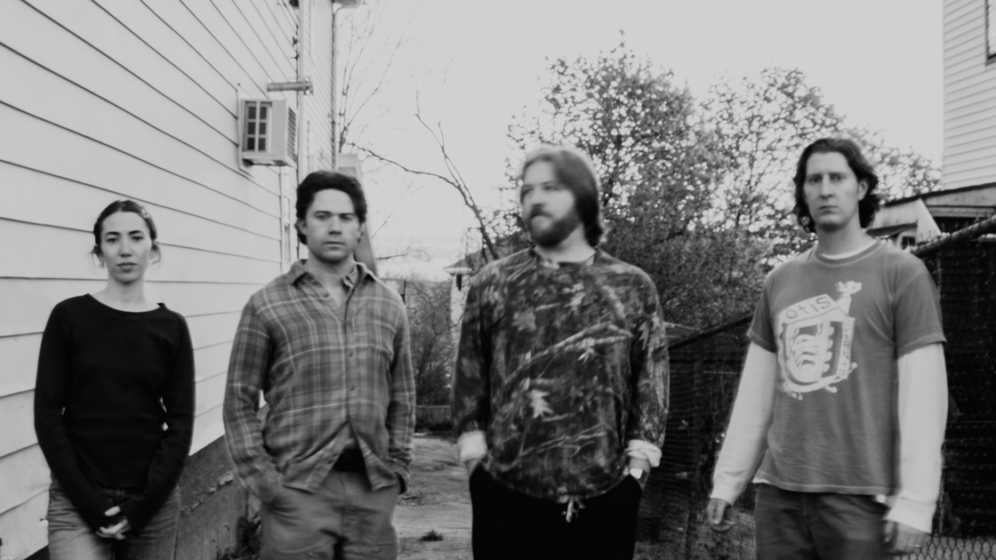 black and white photo of four musicians in an alleyway.