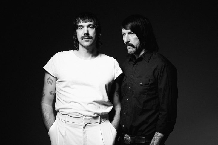 black and white photo of two men. One dressed in white, one dressed in black